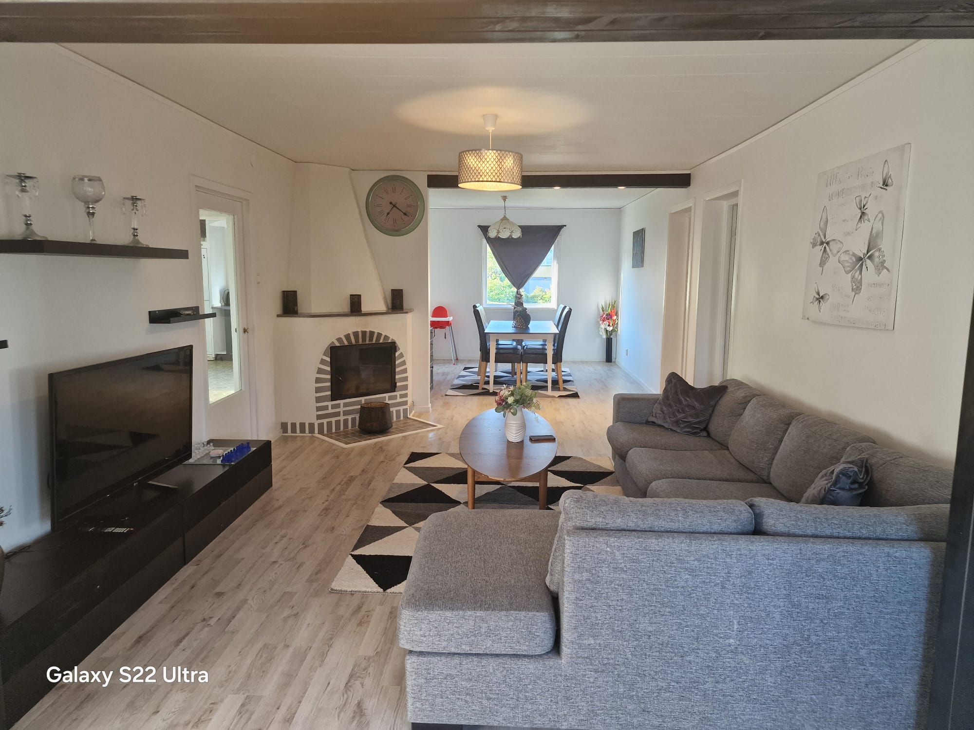 Open-plan living room with grey sofa, fireplace, and dining area beyond